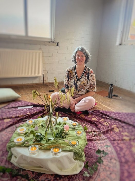 Johanna seated beside a prepared circle with candles and flowers